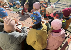 dzieci jedzą kiełbaskę